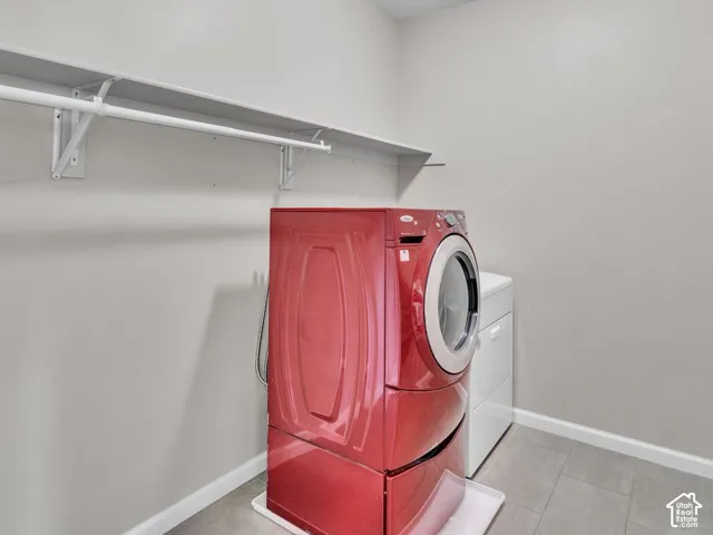 Dedicated utility room featuring gray walls, overhead shelving, and tile flooring