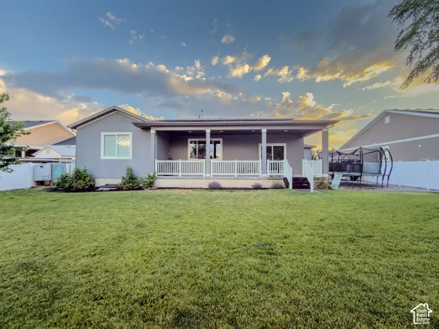 Expansive backyard featuring a manicured lawn, a covered patio, and a white picket railing