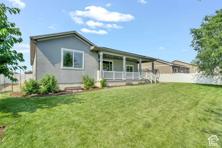 Expansive green lawn with a covered patio featuring white railings and columns