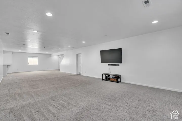 Expansive recreation room featuring gray carpet, recessed lighting, a single window, and a white interior door