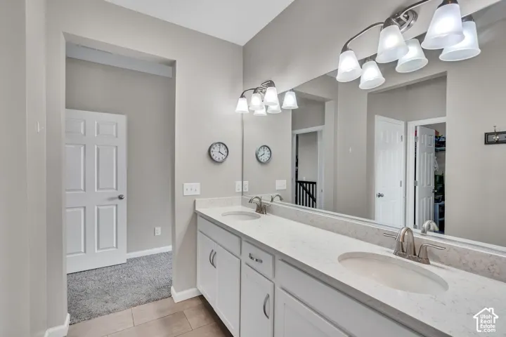 Dual vanity featuring white cabinetry, light-toned countertops, and brushed nickel fixtures