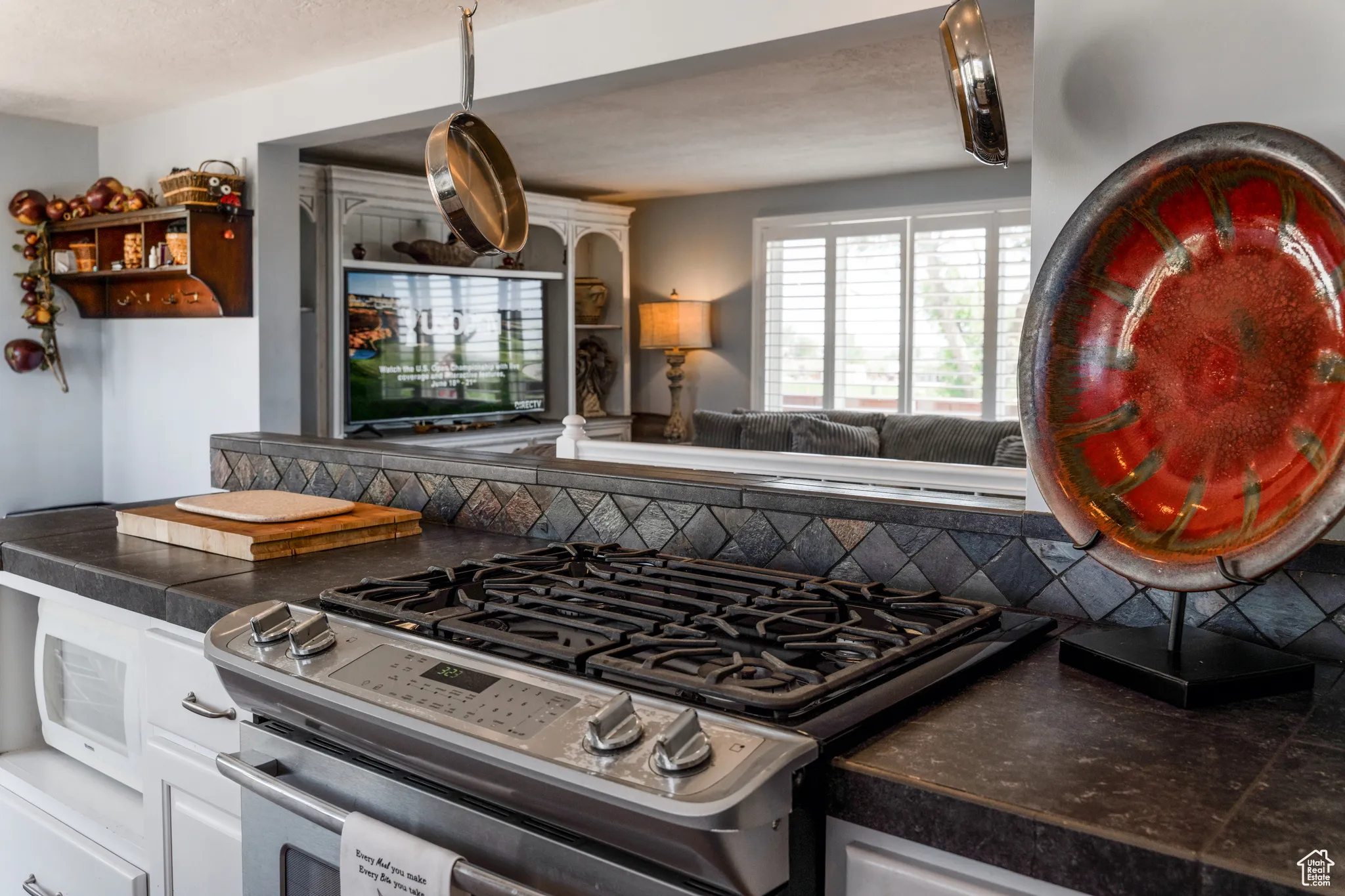 Stainless steel gas range with a dark countertop and diagonal tile backsplash