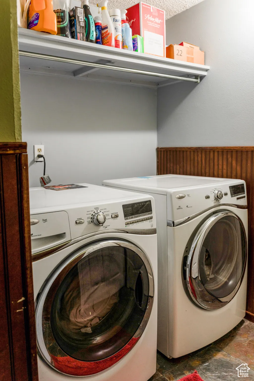 Dedicated laundry area featuring a white shelving unit with a hanging rod, beadboard wainscoting, and wood-finish flooring