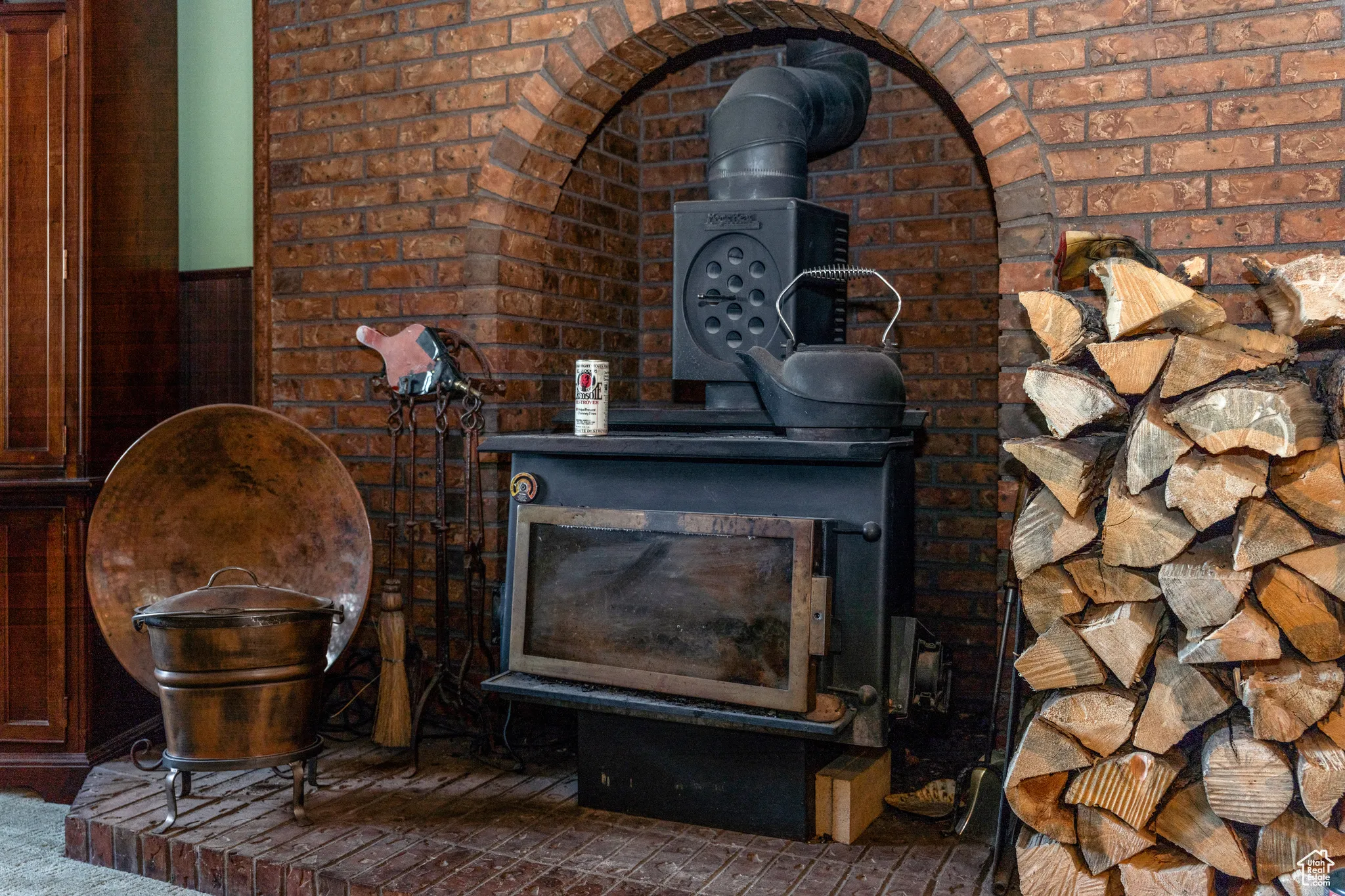 Brick archway framing a black wood-burning stove with a metal flue