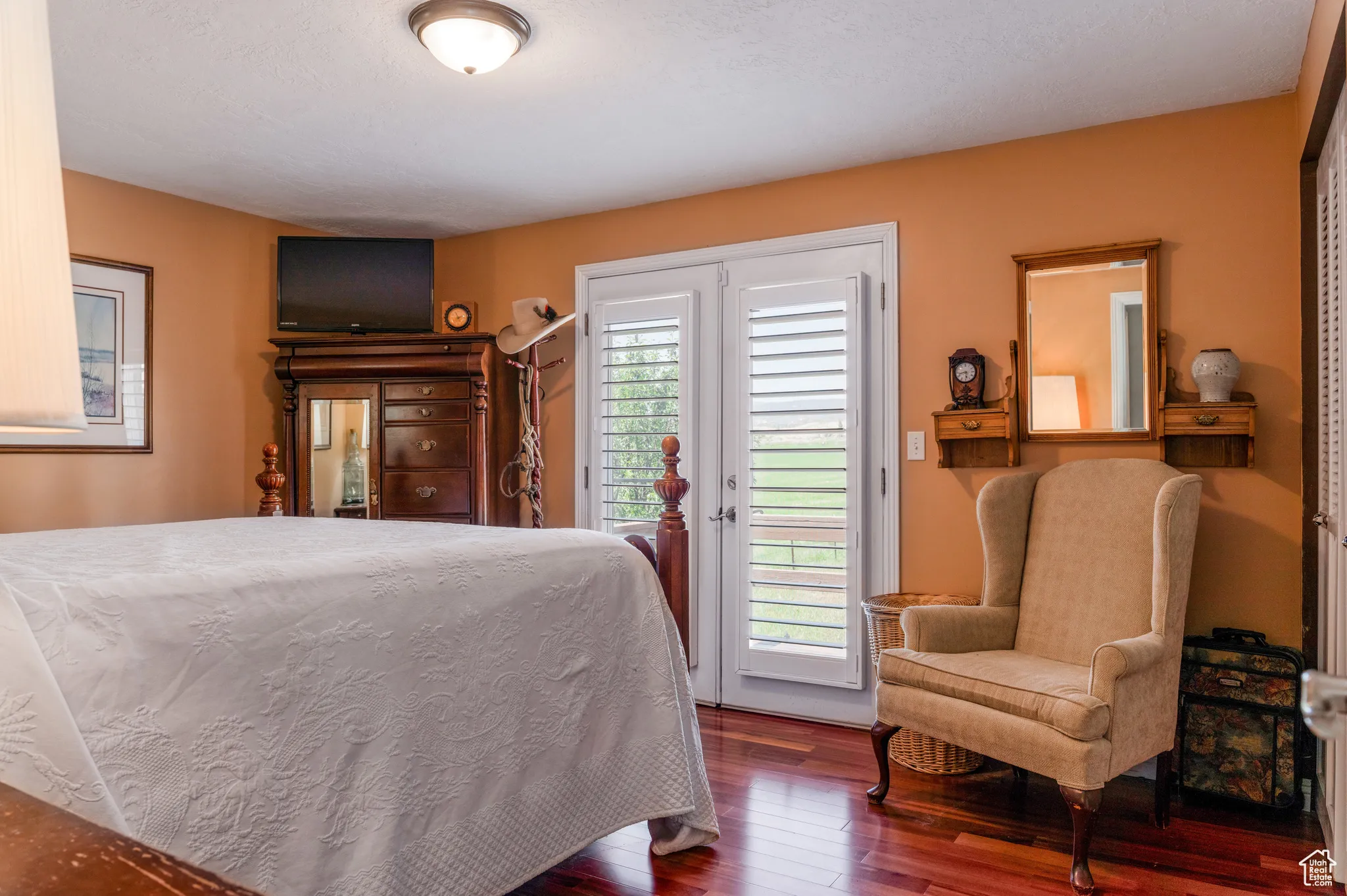 Bedroom featuring rich wood-finish flooring, warm-toned walls, and a ceiling-mounted light fixture
