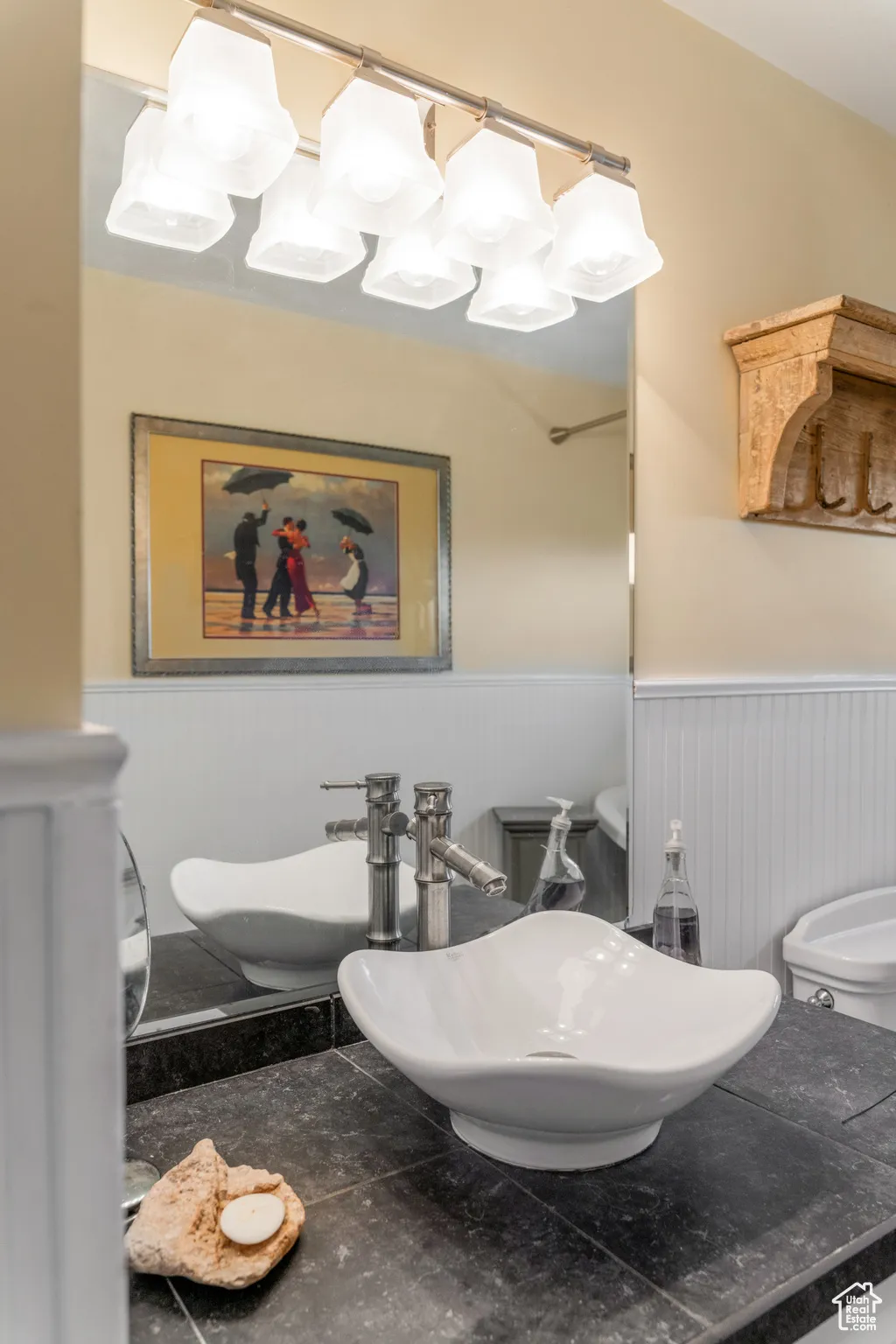 Bathroom vanity with a contemporary vessel sink, dark countertop, and brushed nickel faucet