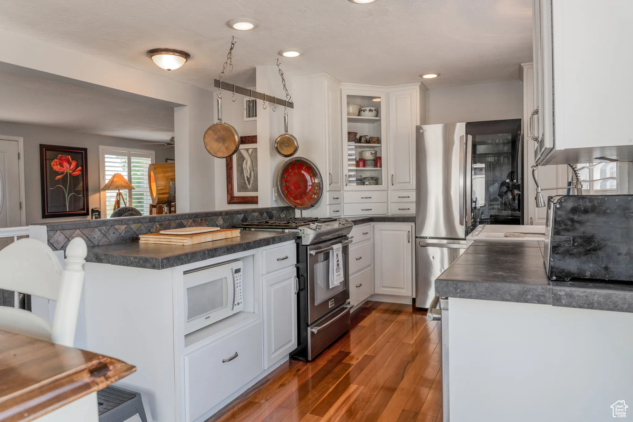 Kitchen featuring wood-finish flooring, white cabinetry, dark countertops, and stainless steel appliances