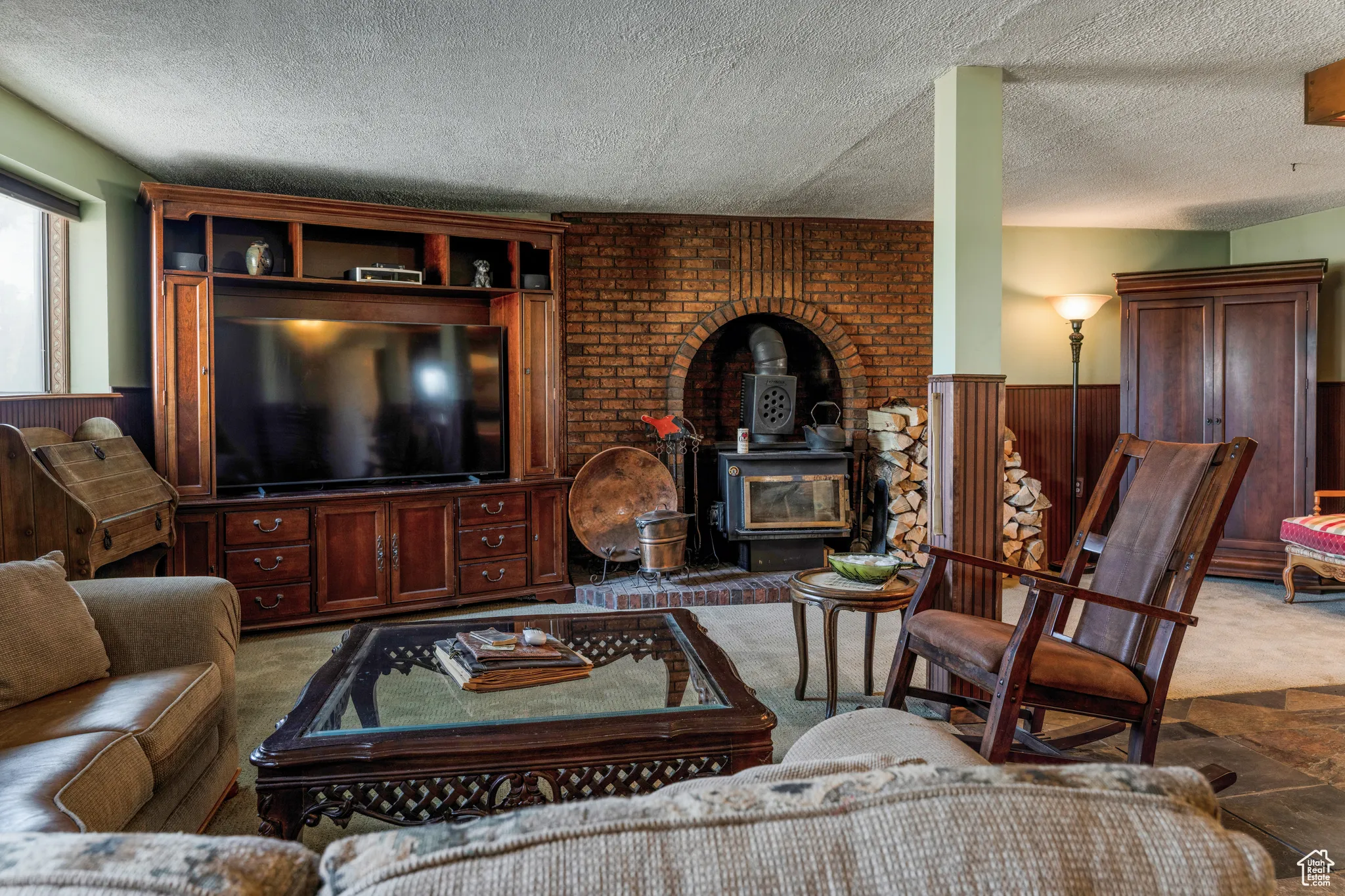 Living area featuring a brick accent wall with an arched alcove, a wood-burning stove, and a built-in media center