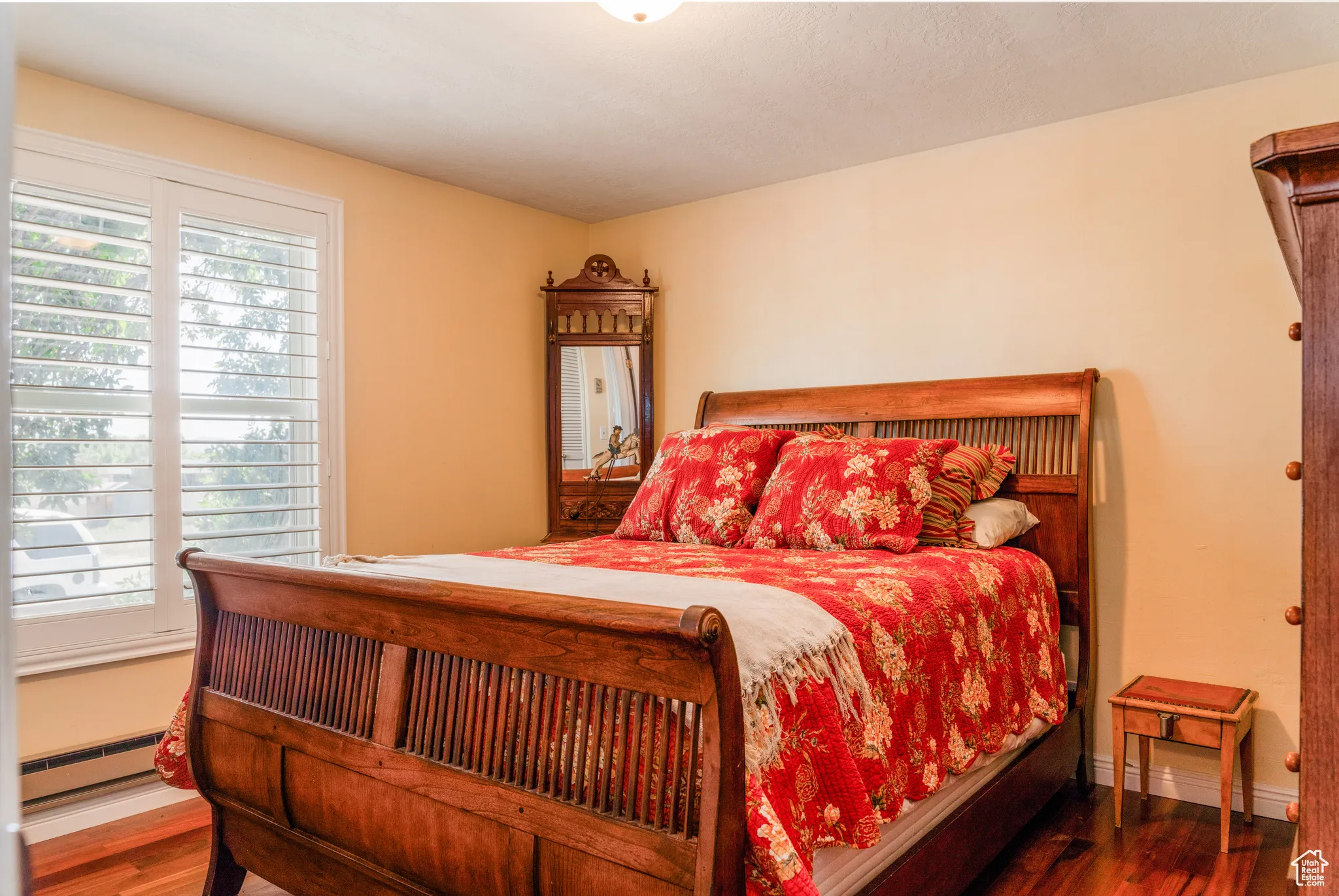 Bedroom featuring wood-finish flooring, plantation shutters, and light yellow wall paint