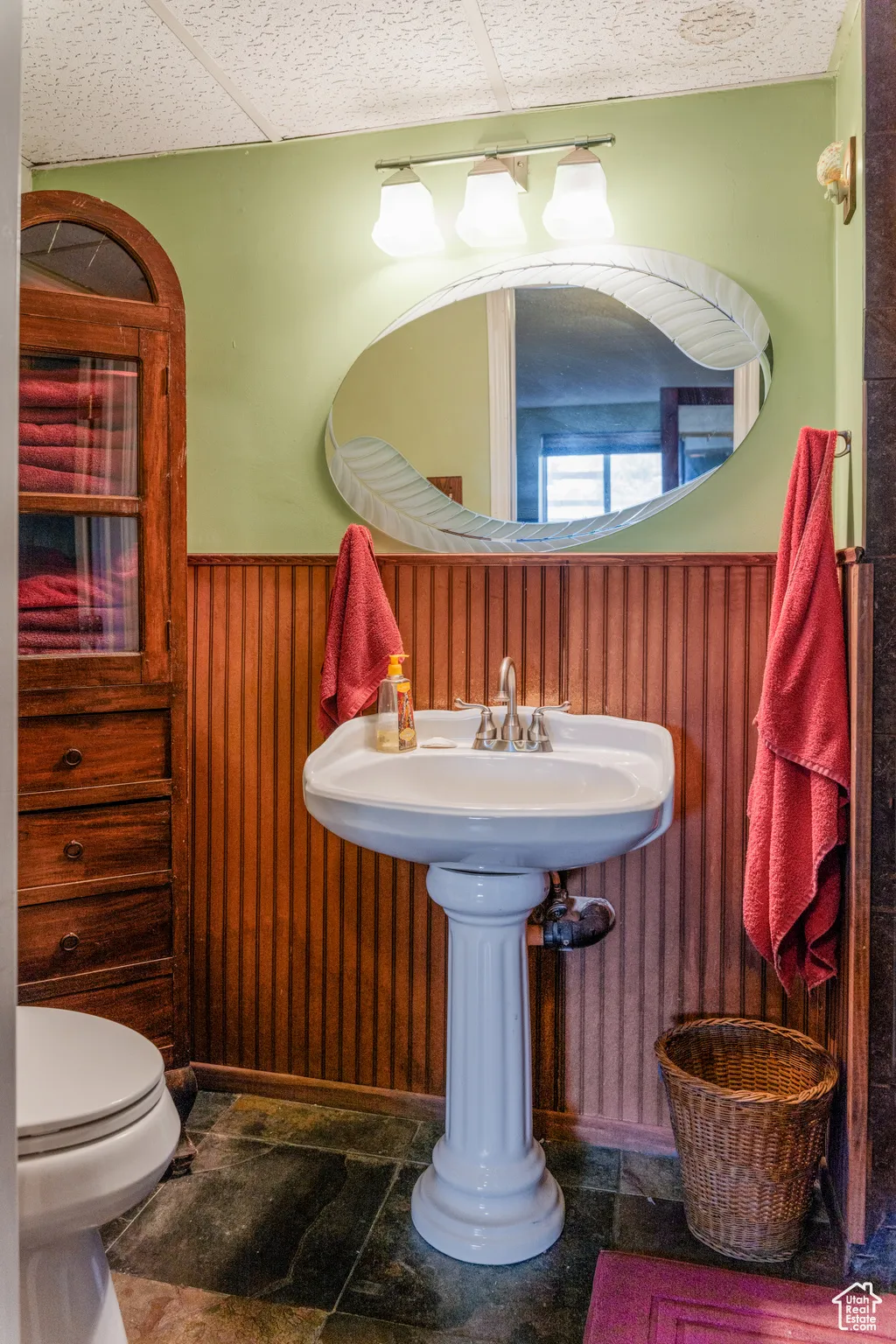 Pedestal sink vanity with a decorative mirror and three-light fixture