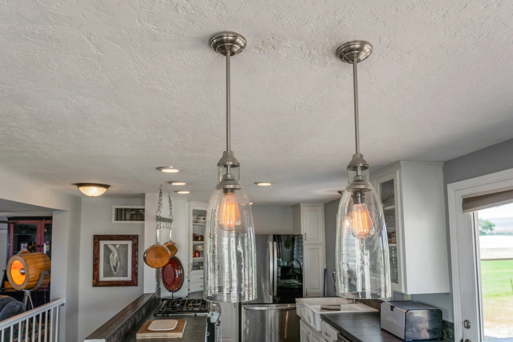 Matching pendant light fixtures featuring clear textured glass shades and exposed Edison-style bulbs