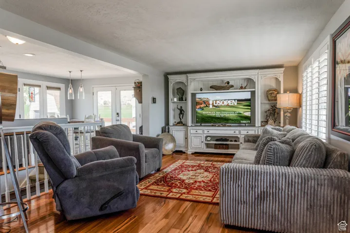 Living area with wood-finish flooring, a built-in entertainment center, and plantation shutters