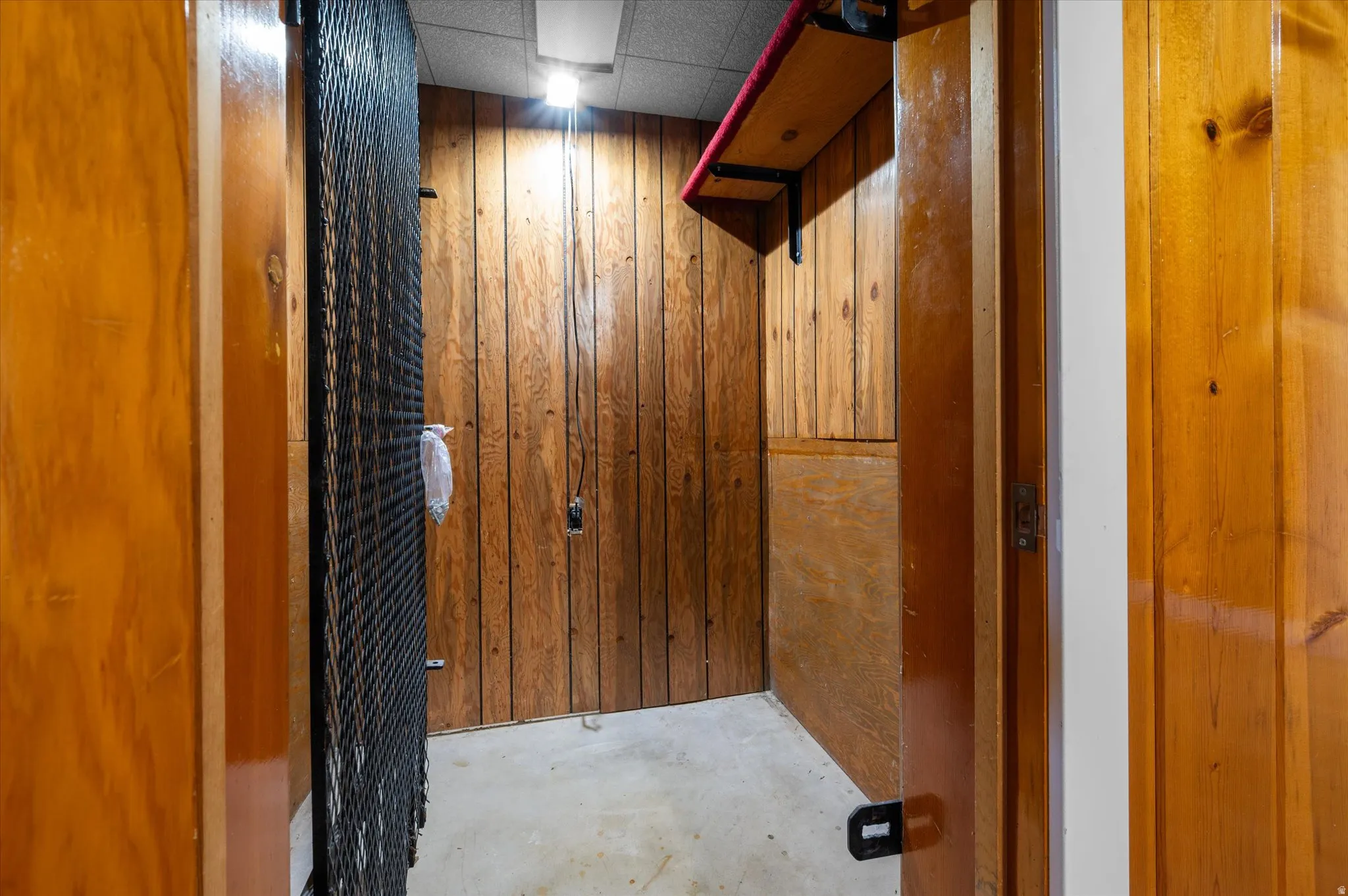 Interior storage area featuring wood paneling, a built-in shelf, and overhead lighting
