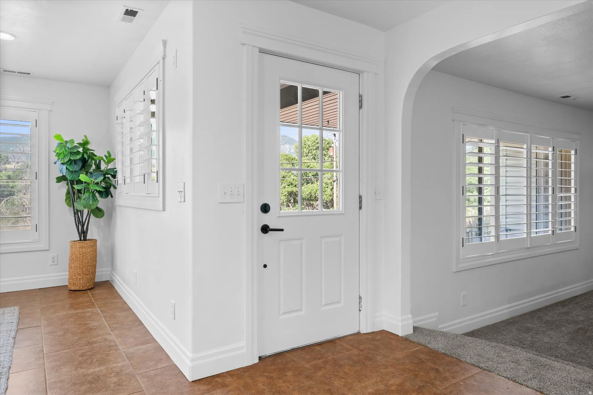 Foyer featuring a paneled entry door with glass inserts, transom window, and tile flooring
