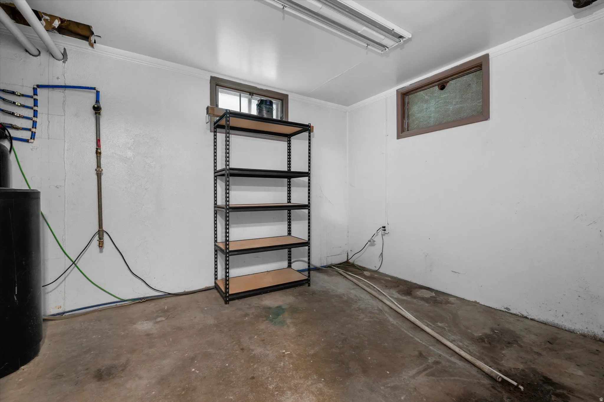 Utility room with concrete flooring, fluorescent overhead lighting, and built-in shelving