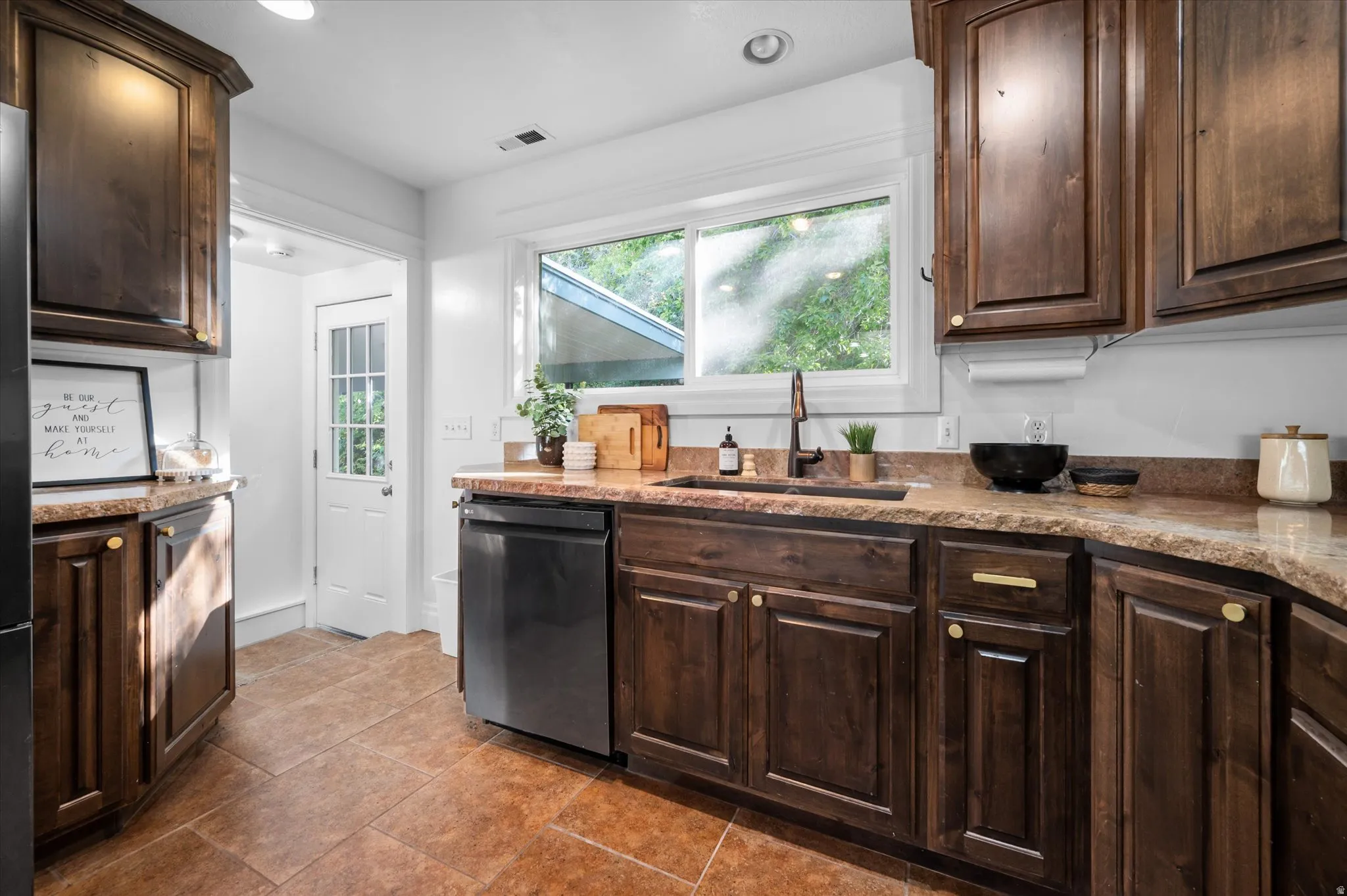 Kitchen featuring wood-finish cabinetry, stone countertops, and a stainless steel dishwasher