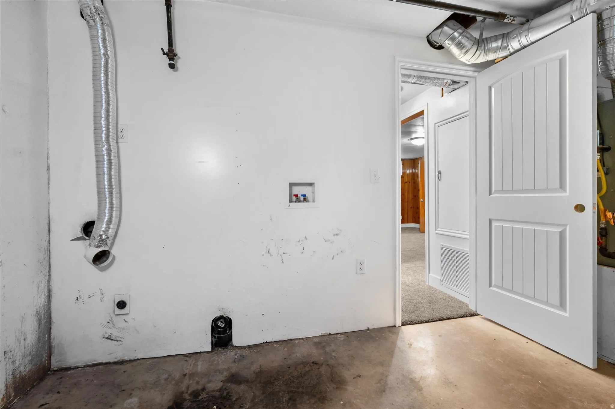 Utility room featuring a washer/dryer hookup, white walls, and concrete flooring