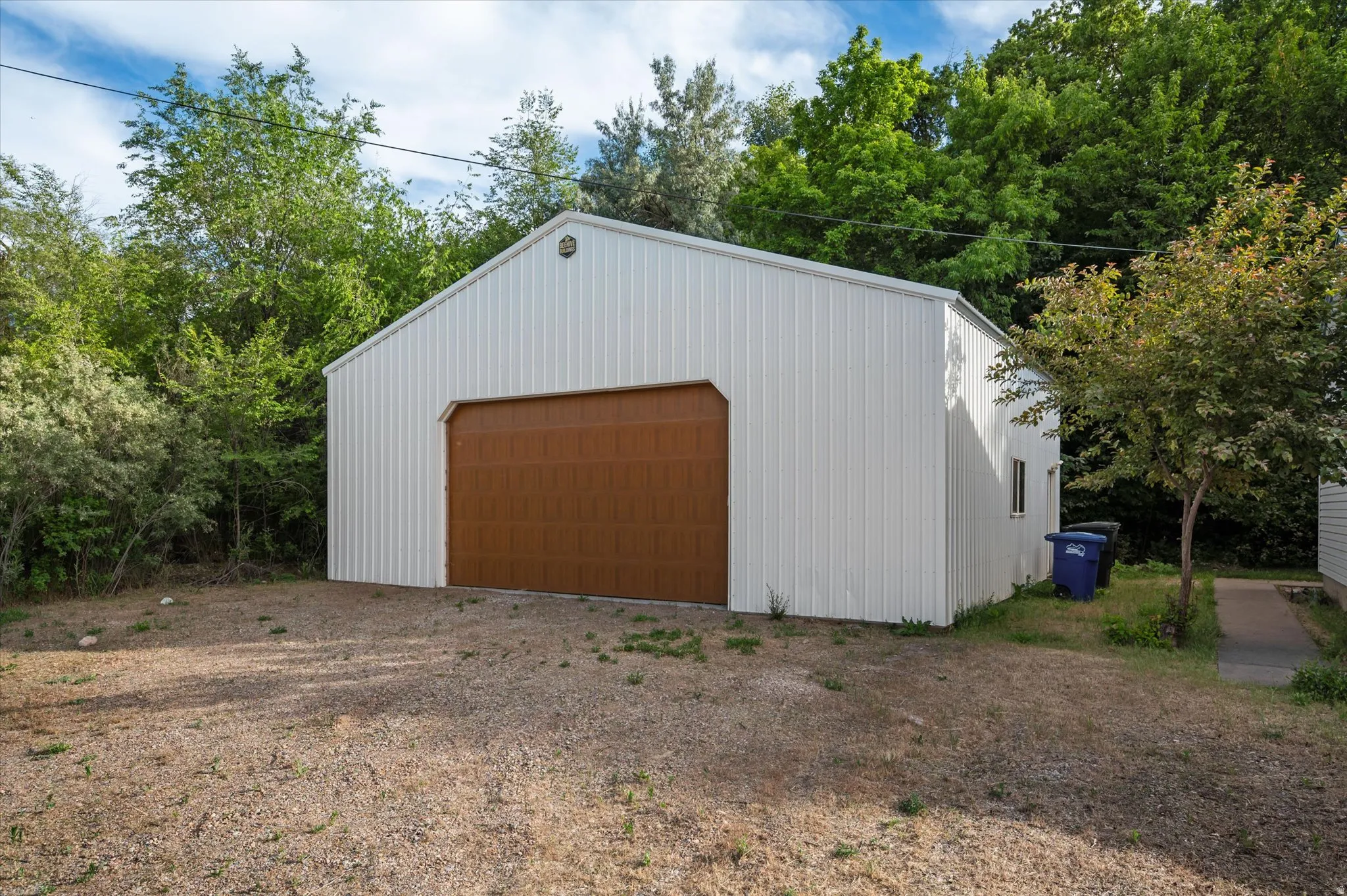 Metal outbuilding featuring a large brown overhead door and a side window