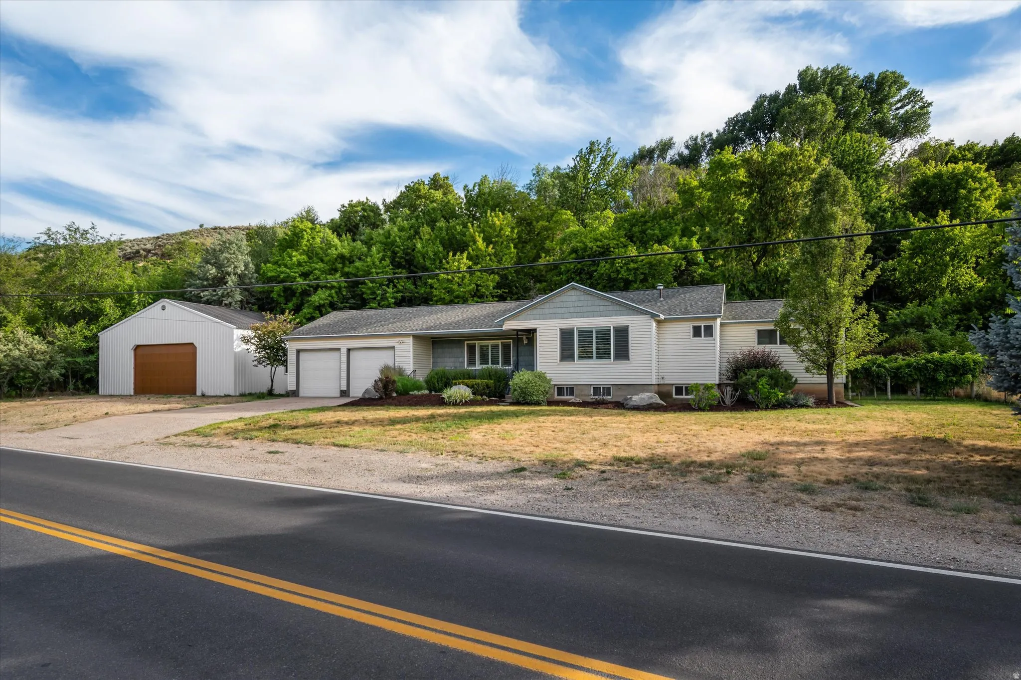 Ranch-style residence featuring a two-car attached garage, additional detached garage, and a sloped shingle roof