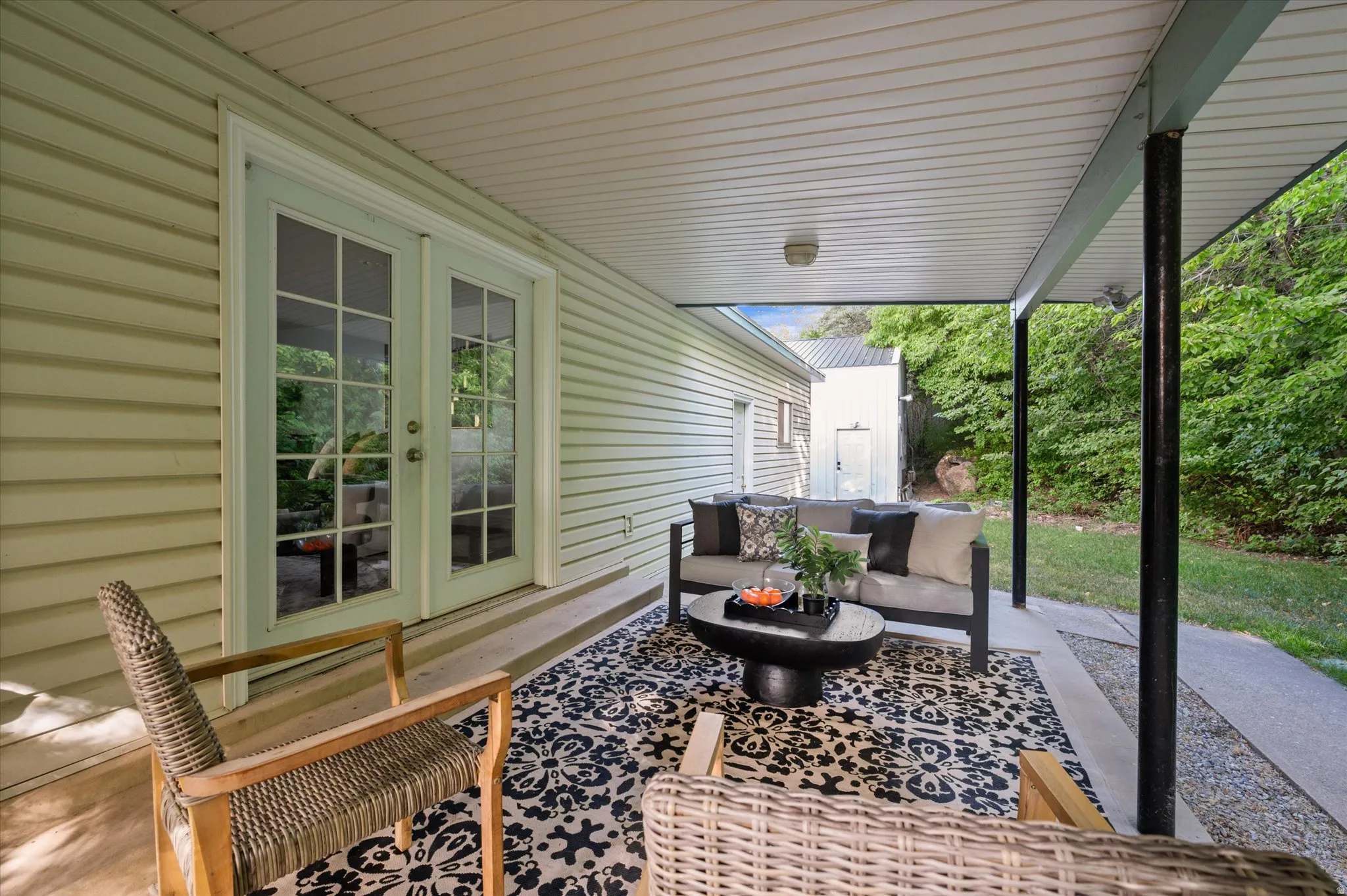 Covered patio featuring a white beadboard ceiling, concrete flooring, and support pillars