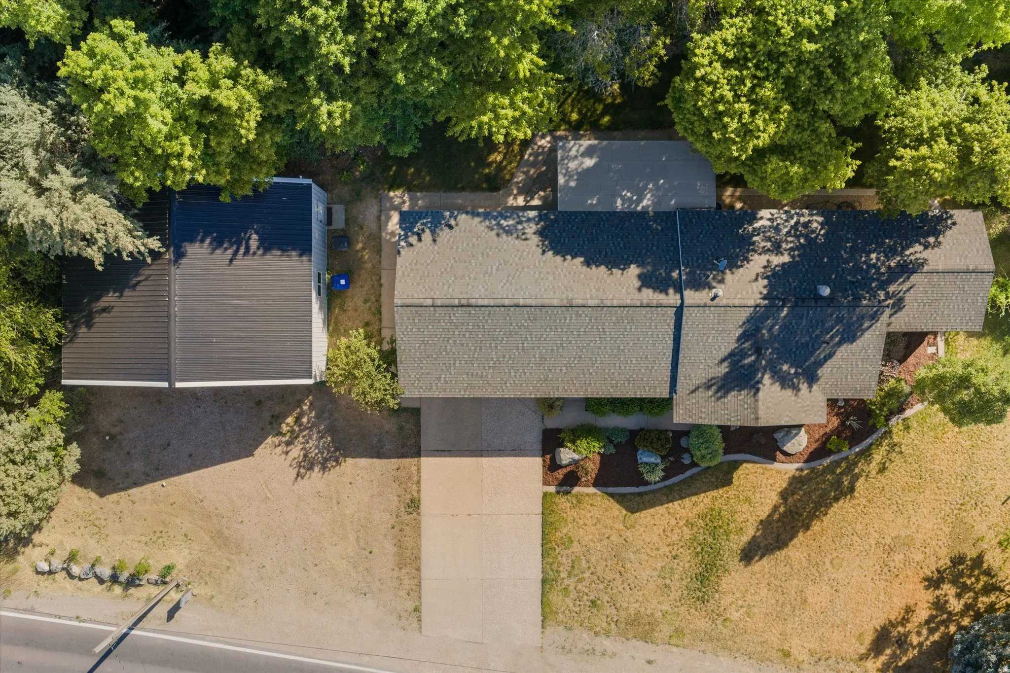 Overhead property view featuring two distinct rooflines, including a dark grey shingle roof and a standing seam metal roof