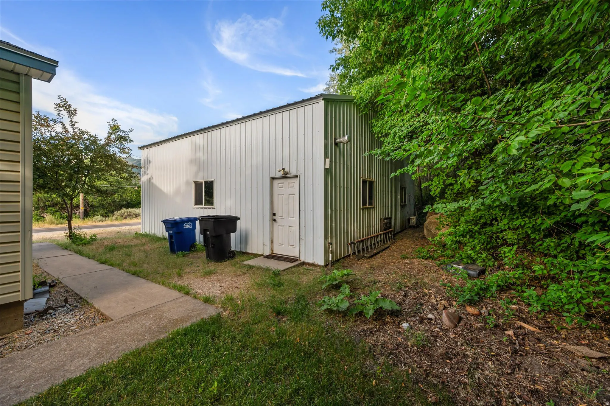Detached building with white corrugated metal siding and a white entry door