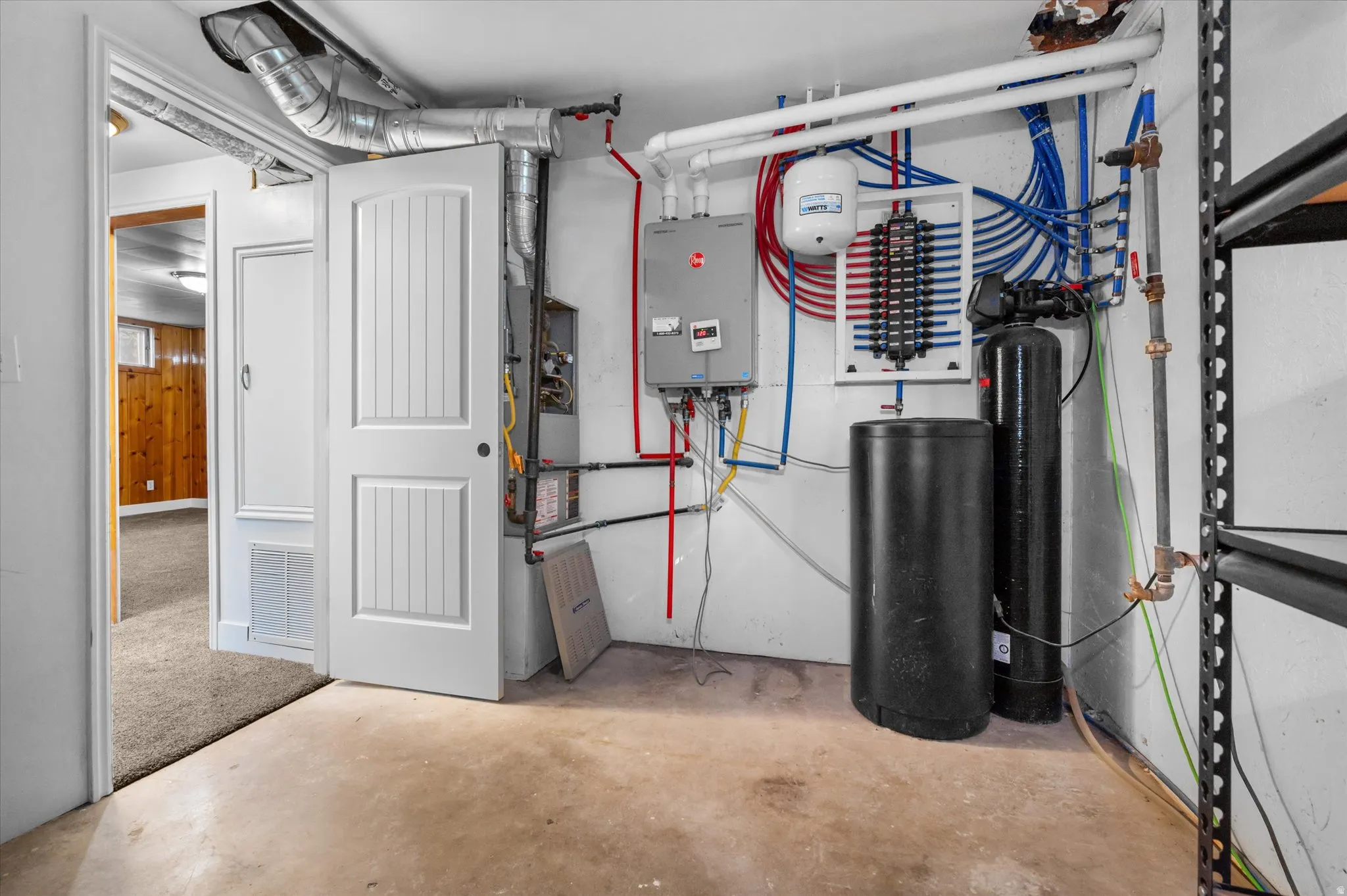 Mechanical room featuring a tankless water heater, water treatment system, and HVAC unit with exposed ductwork