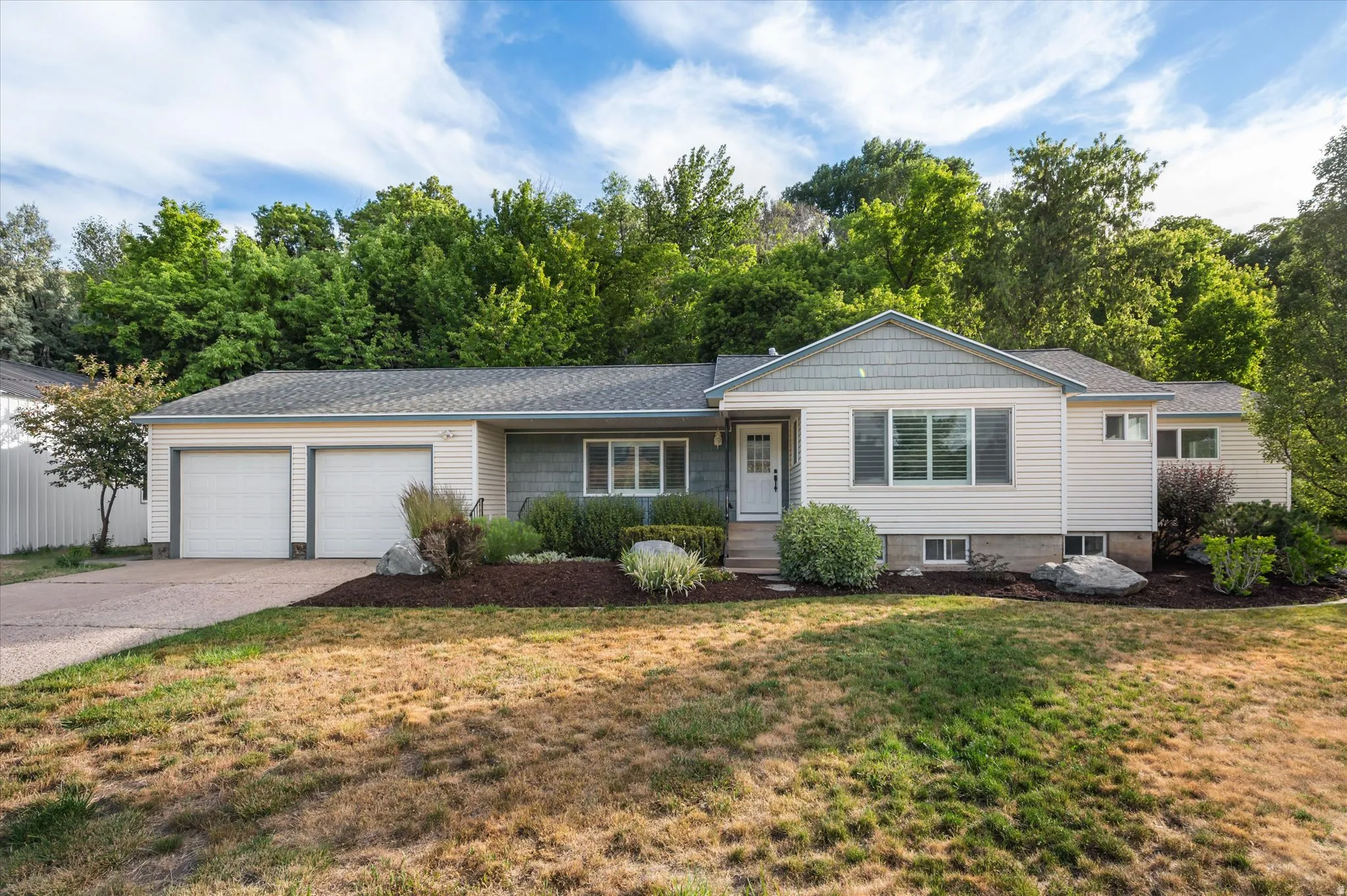 Ranch-style exterior with a two-car garage, gray shake siding accents, and a covered entry