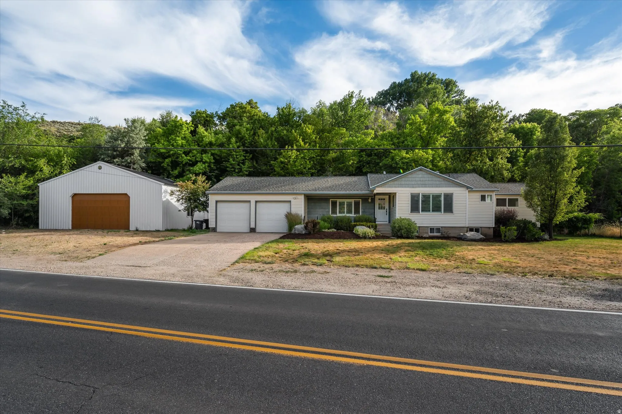 Ranch-style residence featuring a two-car attached garage and a separate large outbuilding with a single wide door