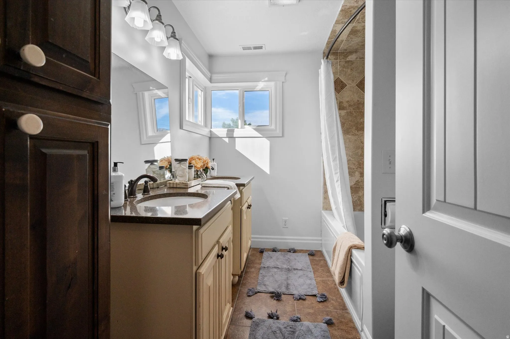 Bathroom with dual vanity featuring undermount sinks, bronze-finish faucets, and stone countertops