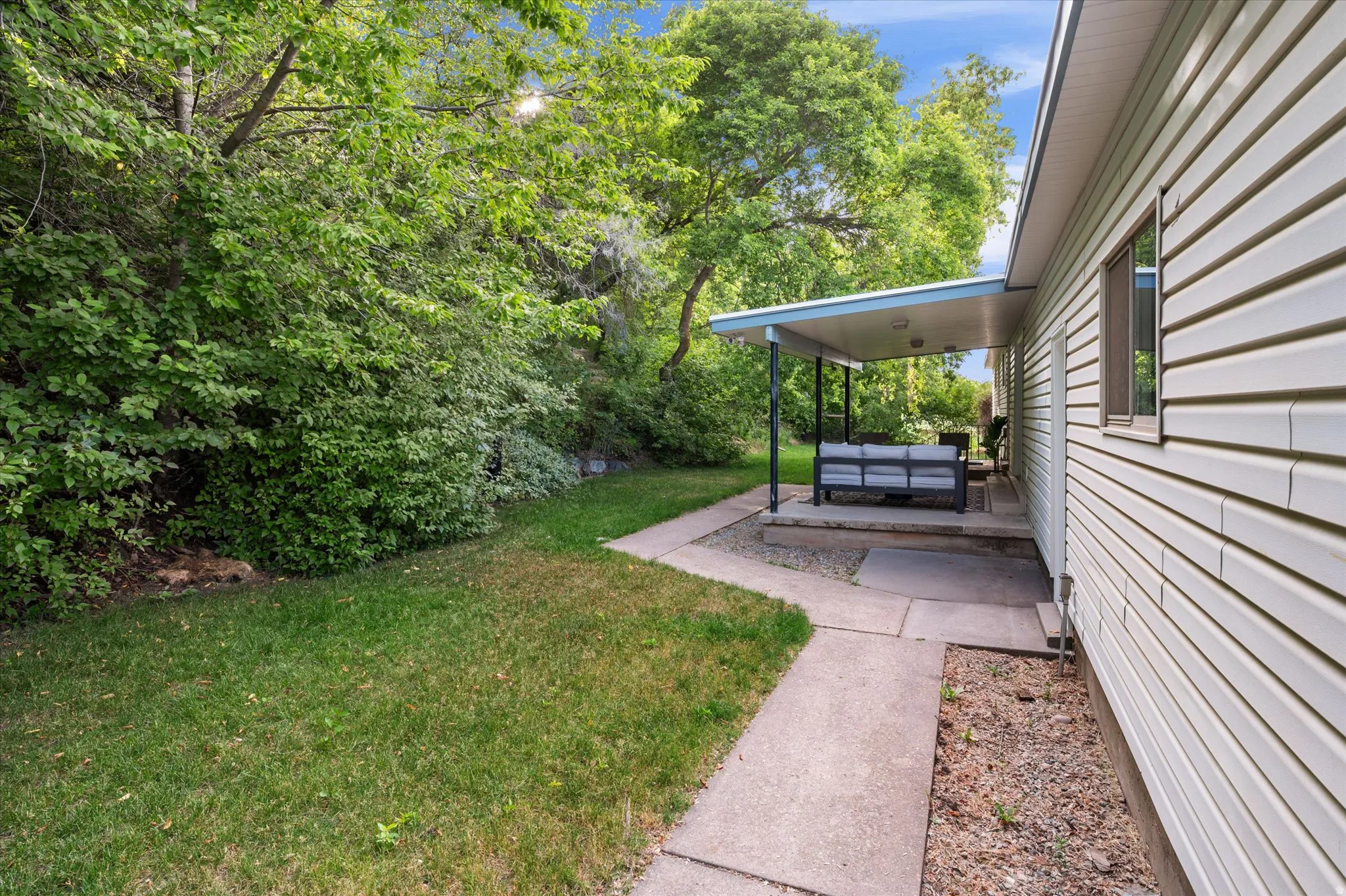 Side exterior with a covered patio area and mature perimeter landscaping