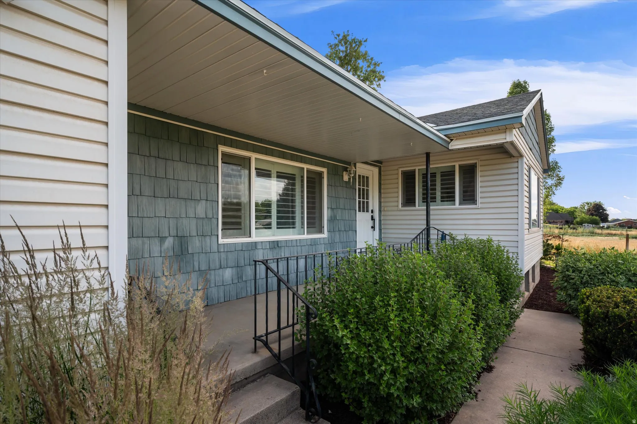 Exterior featuring horizontal siding, teal shake siding, white trim, and a covered porch entry
