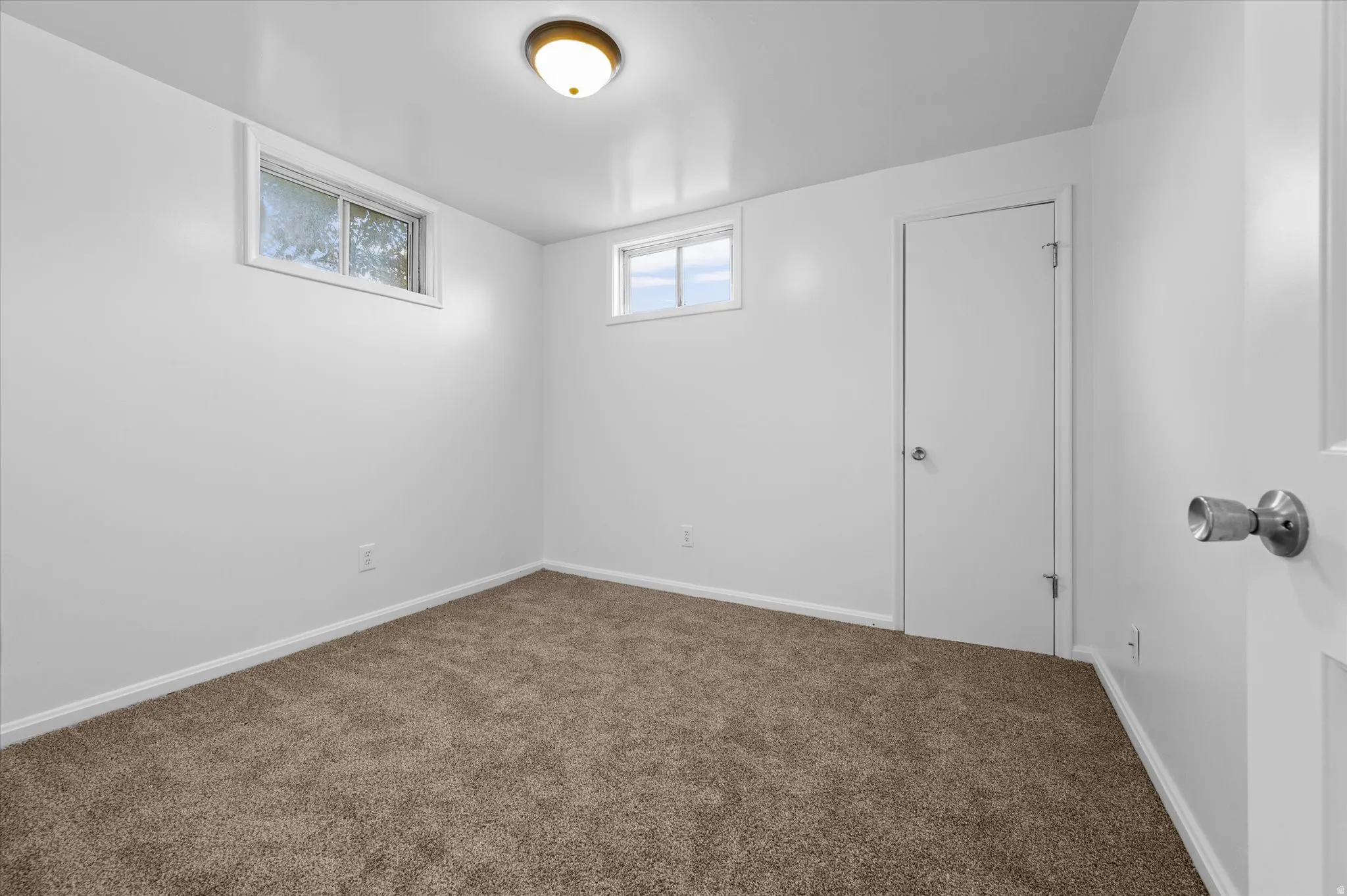 Carpeted room featuring white walls, white trim, and two windows