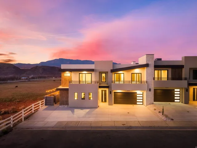 Modern multi-level exterior featuring stucco siding, stone accents, and dark-framed windows