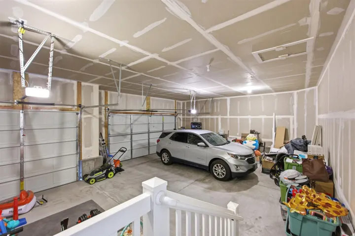 Spacious garage featuring two overhead doors, exposed framing, and a concrete floor