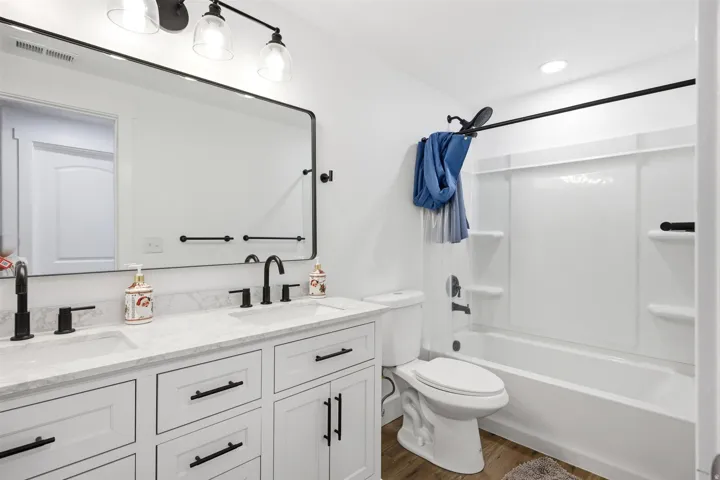 Bathroom featuring a dual vanity with white shaker cabinets, matte black hardware, and light-toned countertops
