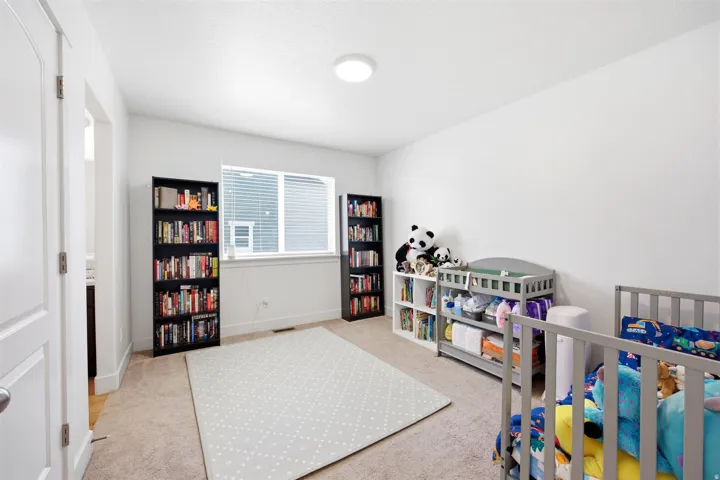Carpeted room featuring a large window with blinds, white walls, and a ceiling-mounted light fixture