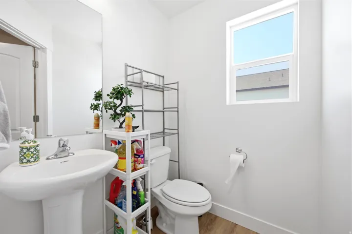 Pedestal sink with chrome faucet, large wall mirror, and white toilet
