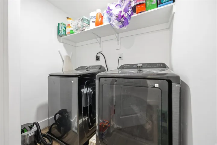 Dedicated utility area featuring white walls, wood-finish flooring, a wall-mounted white storage shelf, and electrical outlets