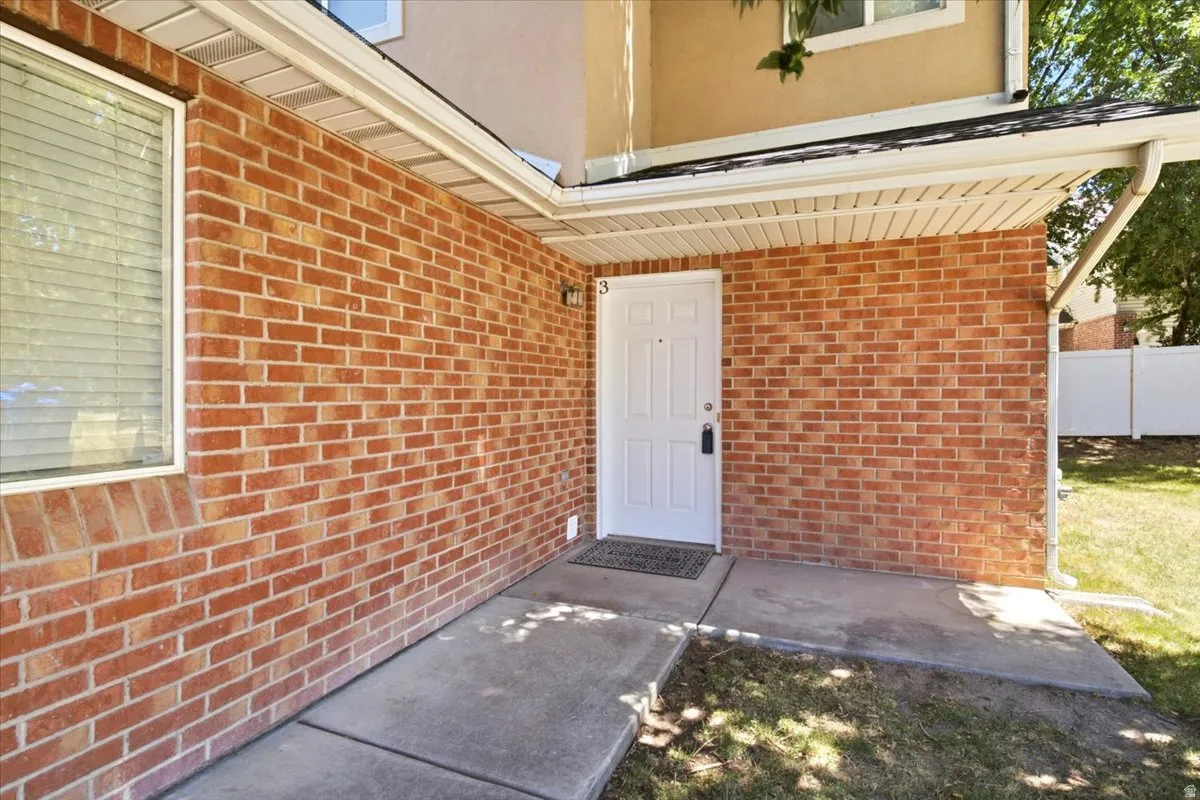 Brick facade entry featuring a white paneled door, covered porch, and concrete walkway