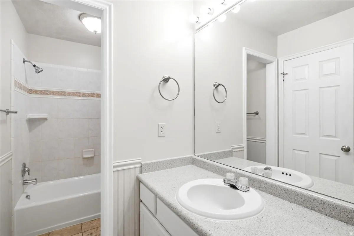 Bathroom featuring a white vanity with an integrated sink, a speckled countertop, and a large wall-mounted mirror