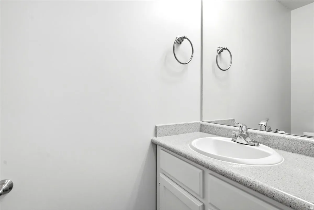 Bathroom vanity featuring a speckled countertop, integrated sink, and chrome faucet