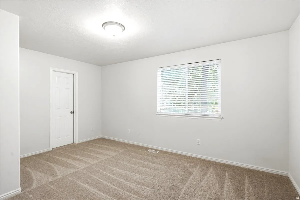 Room featuring light-colored walls and patterned carpet flooring
