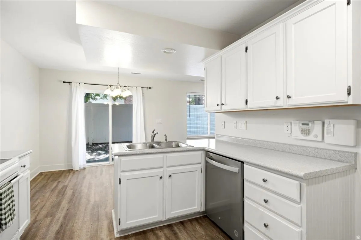 Kitchen featuring white cabinetry with dark hardware, a stainless steel dishwasher, and a double basin sink