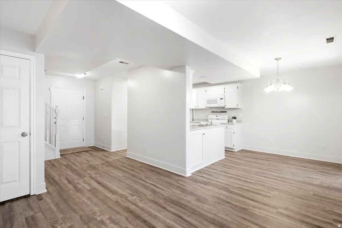 Open-concept living area with wood-finish flooring, white walls, and bright overhead lighting
