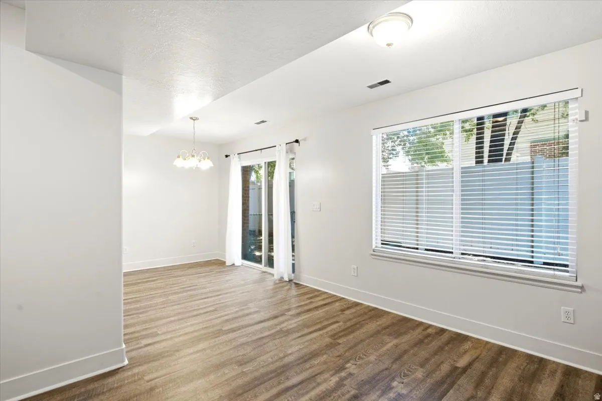 Open-concept room featuring wood-finish flooring, a large window with horizontal blinds, and a glass sliding door