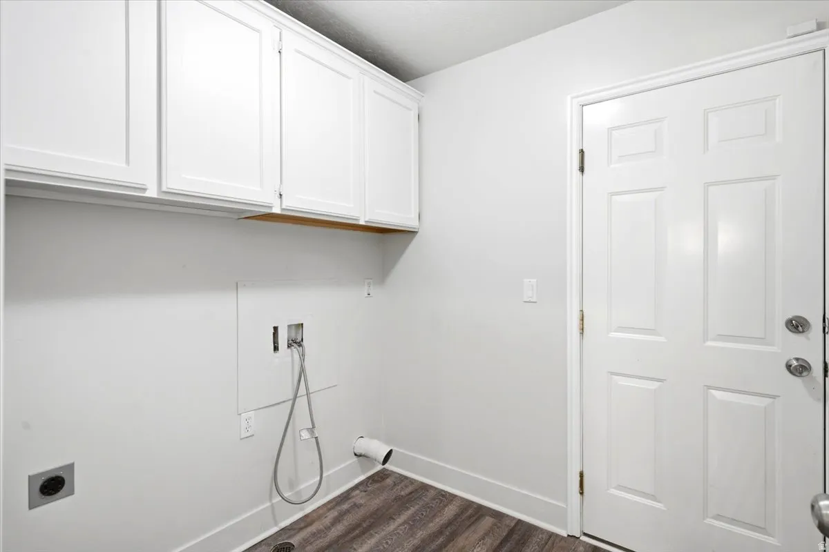 Laundry area featuring white shaker-style cabinetry, wood-finish flooring, and a white paneled door
