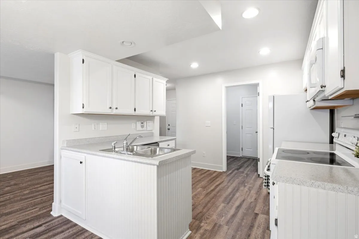Kitchen featuring white cabinetry, light-colored countertops, and wood-finish flooring