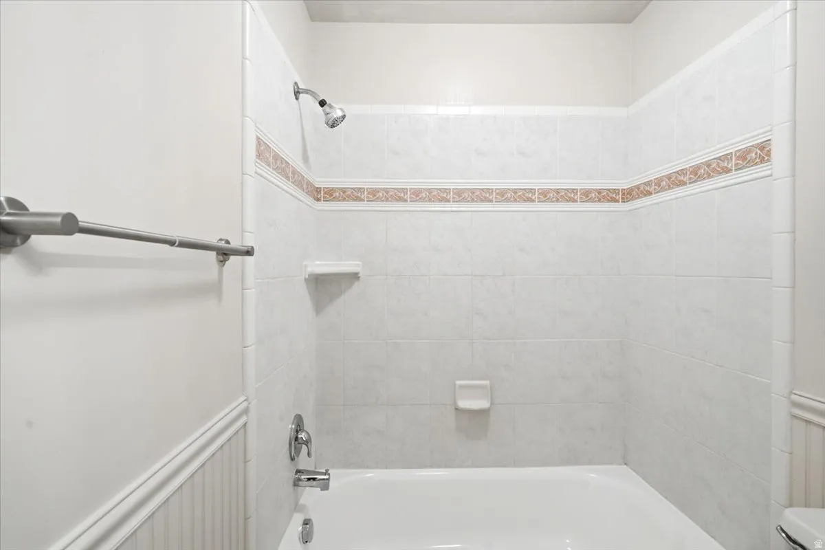 Shower-tub combination featuring light-toned tile surround with decorative accent banding