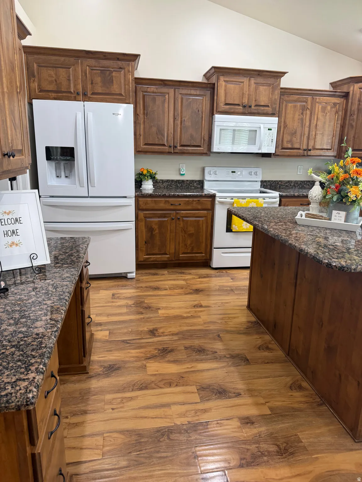 Kitchen featuring wood-finish flooring, dark granite countertops, and wood cabinetry